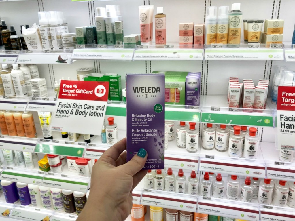hand holding weleda oil with products in background