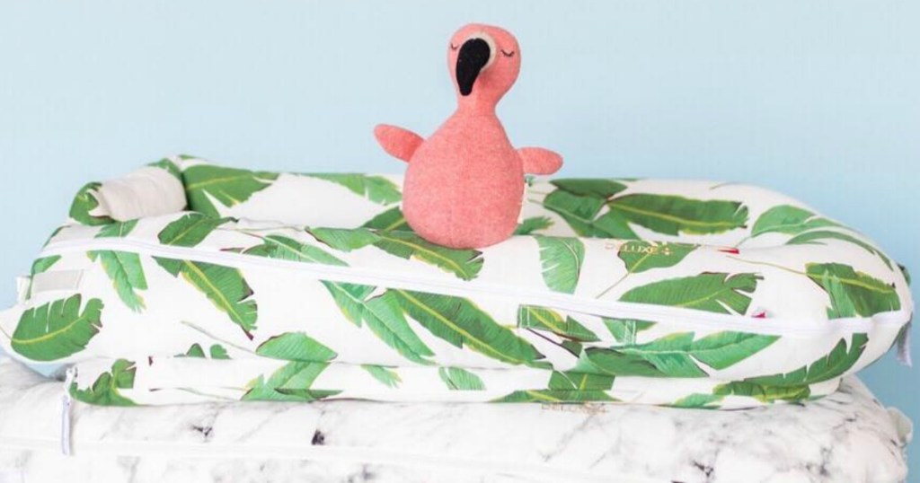 Small flamingo stuffed animal on a stack of dockatot baby sleeper beds