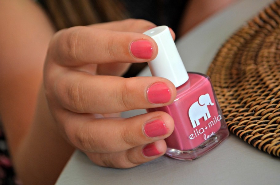 childs hand holding a bottle of nail polish