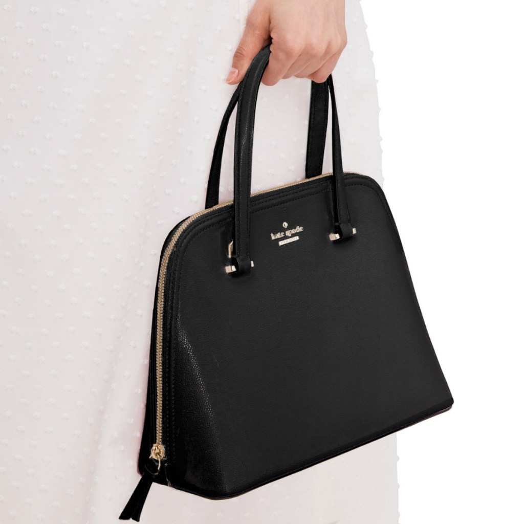 Hand holding Kate Spade brand black satchel bag