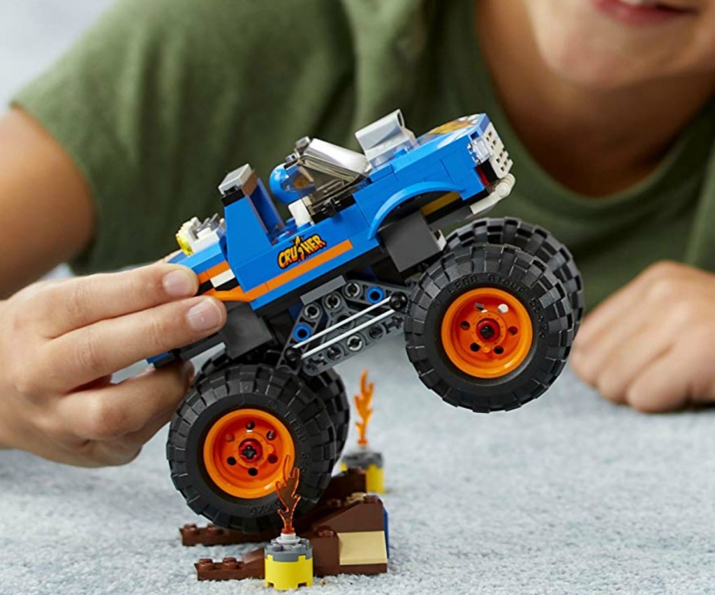 Boy playing with a LEGO monster truck set, fully constructed