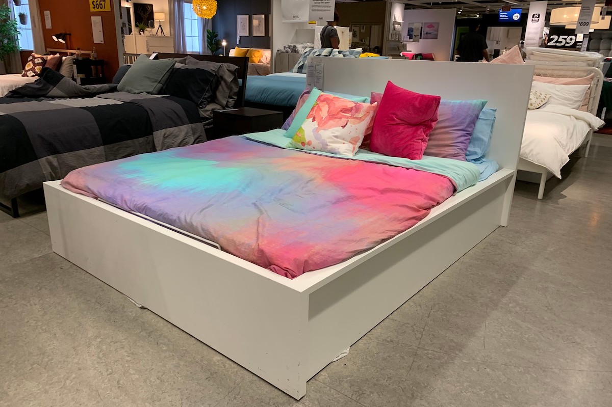 white MALM bed with tye dye comforter in IKEA store