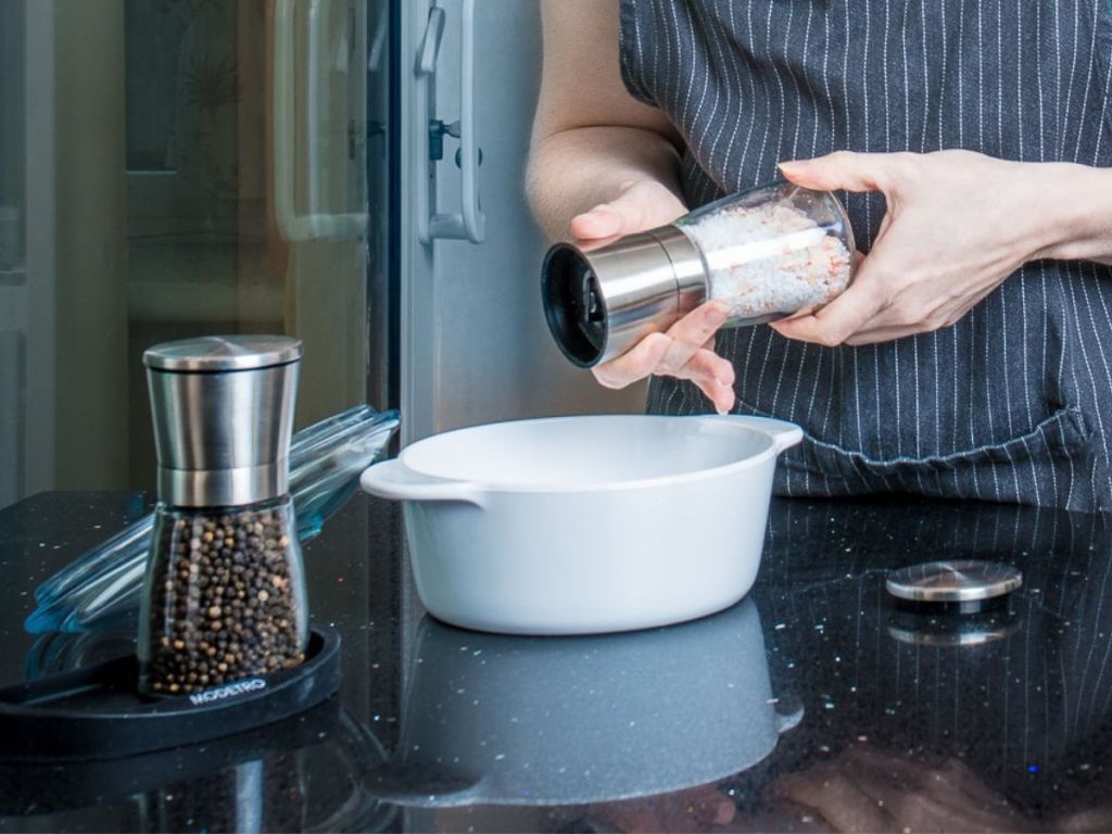 woman holding salt ginger over bowl in kitchen