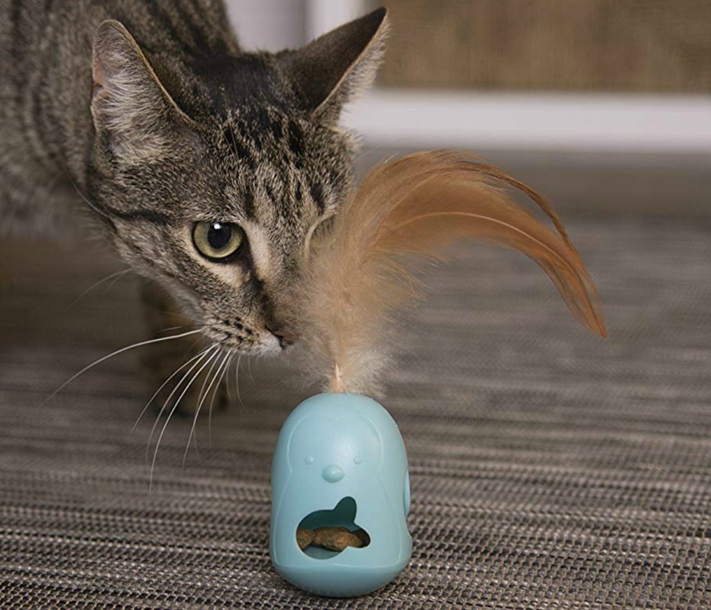 Cat playing with tip-able treat dispenser 