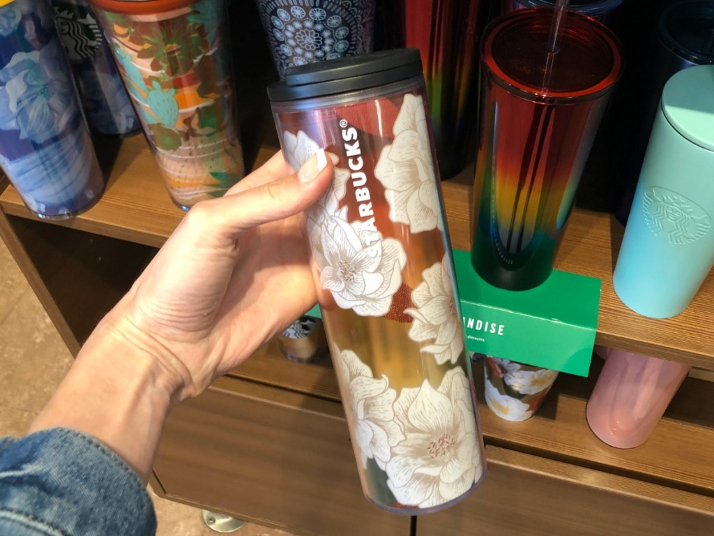 Large Starbucks brand cup with top in flower print in hand, in-store