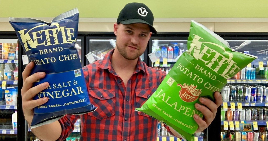 man holding up 2 bags of kettle chips