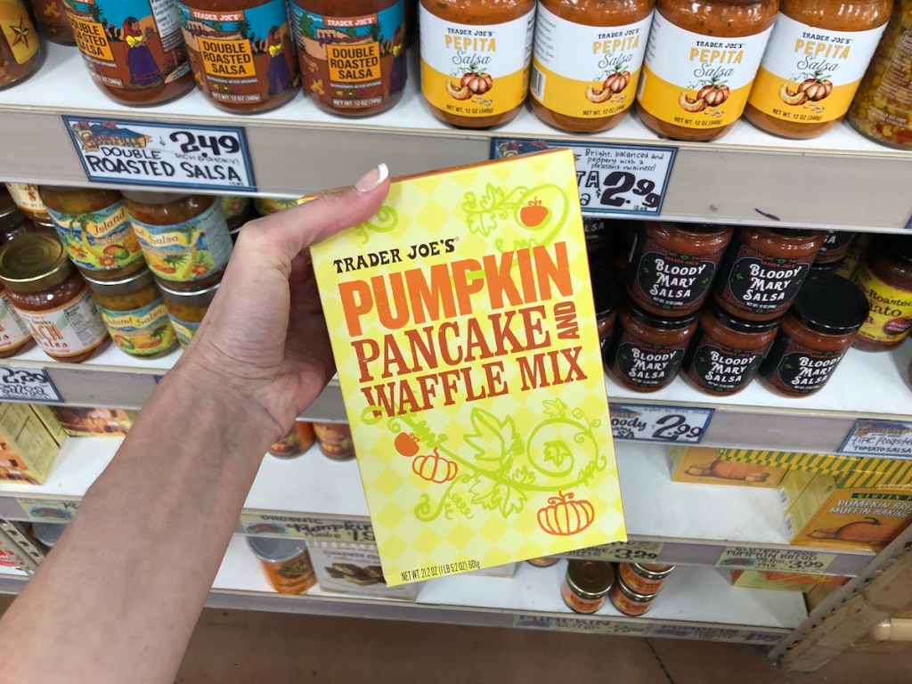 women's hand holding Trader Joe's pumpkin pancake and waffle mix in store