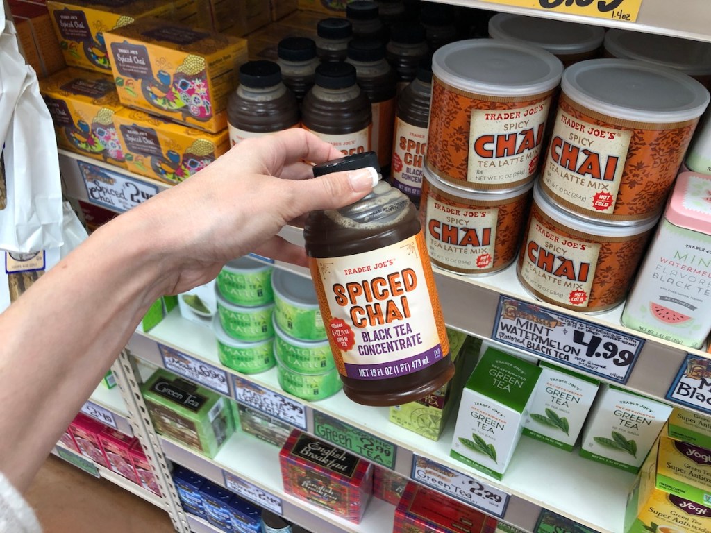 Women's hand holding Trader Joe's Spiced Chai Black Tea Concentrate in Store