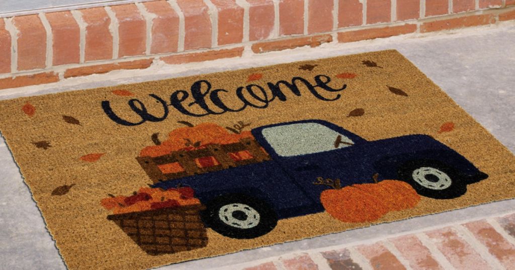 Welcome mat with pick up truck and pumpkins on door steps