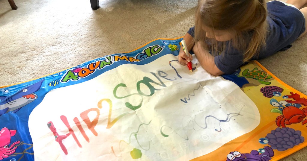 girl drawing on coloring mat on white carpet