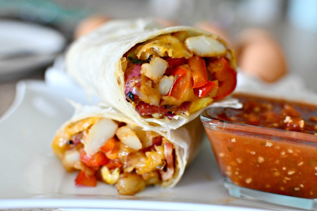 bacon egg and potato breakfast burrito on a plate with salsa