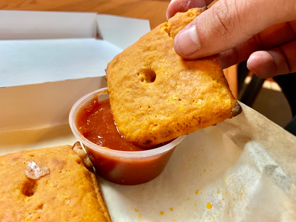 hand holding cheez-it slice into dipping sauce