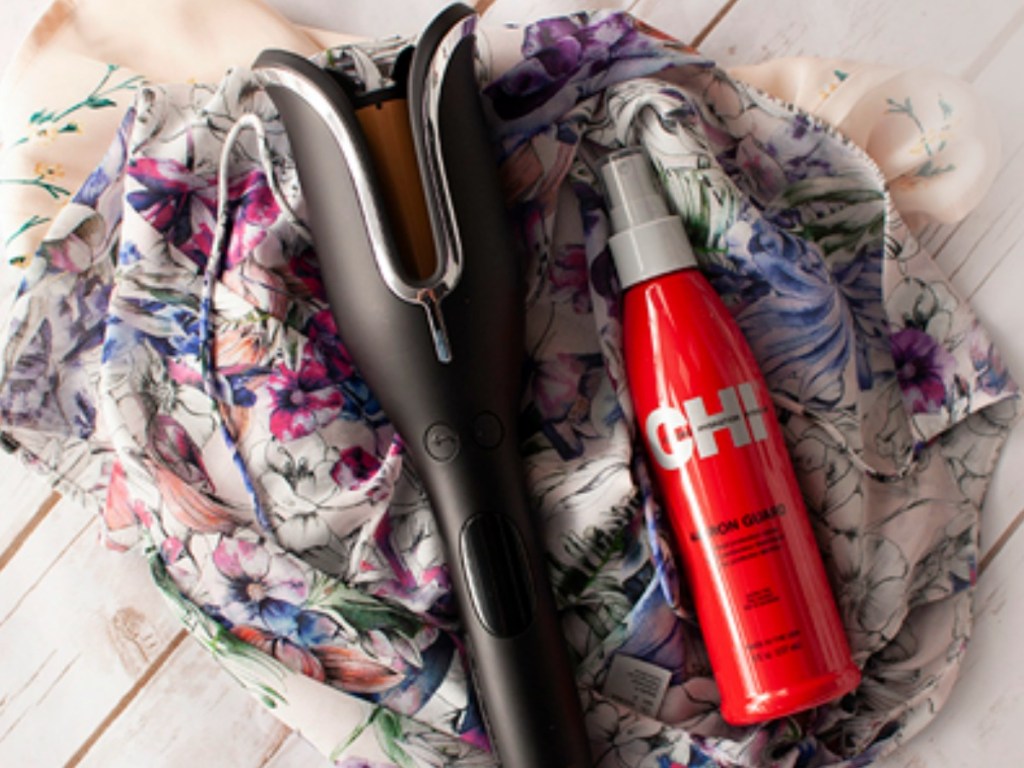 hair iron laying on shirt next to bottle of spray