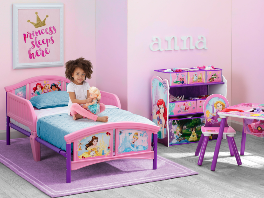disney princess toddler bed with little girl sitting on it