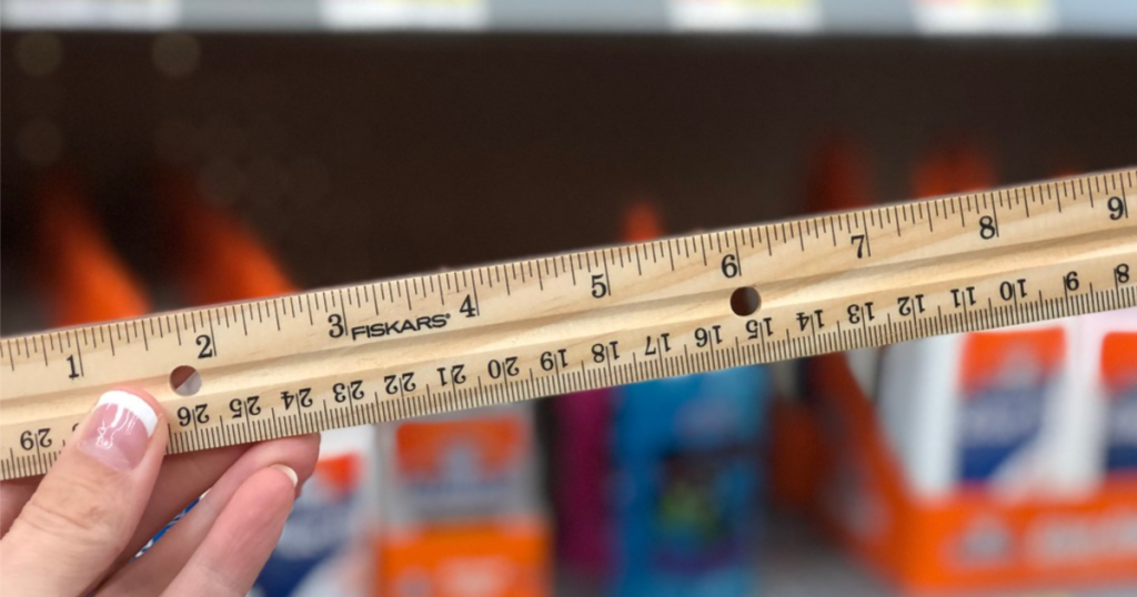 hand holding fiskars wooden ruler with blurred background