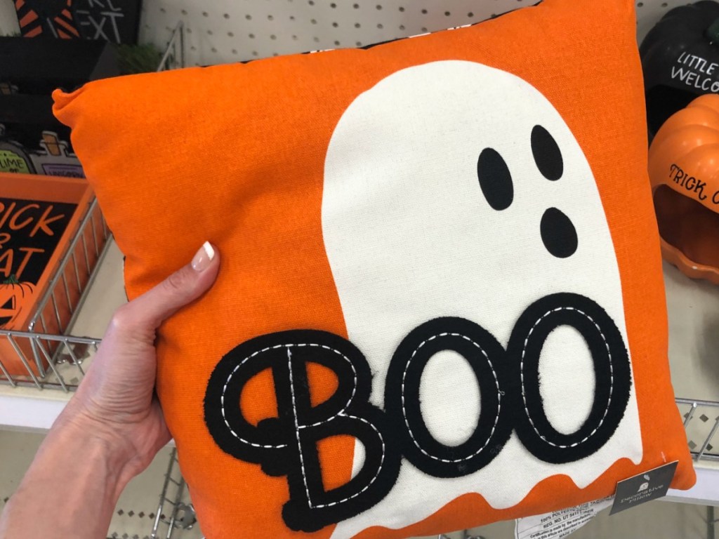 hand holding orange pillow with ghost on it
