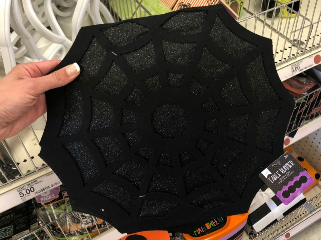 hand holding black mat that looks like a spider web decoration