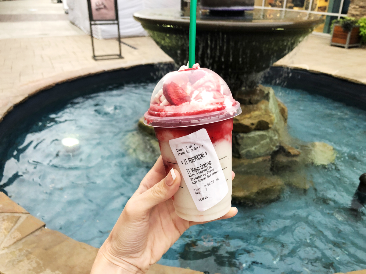 hand holding IT Frappuccino by fountain