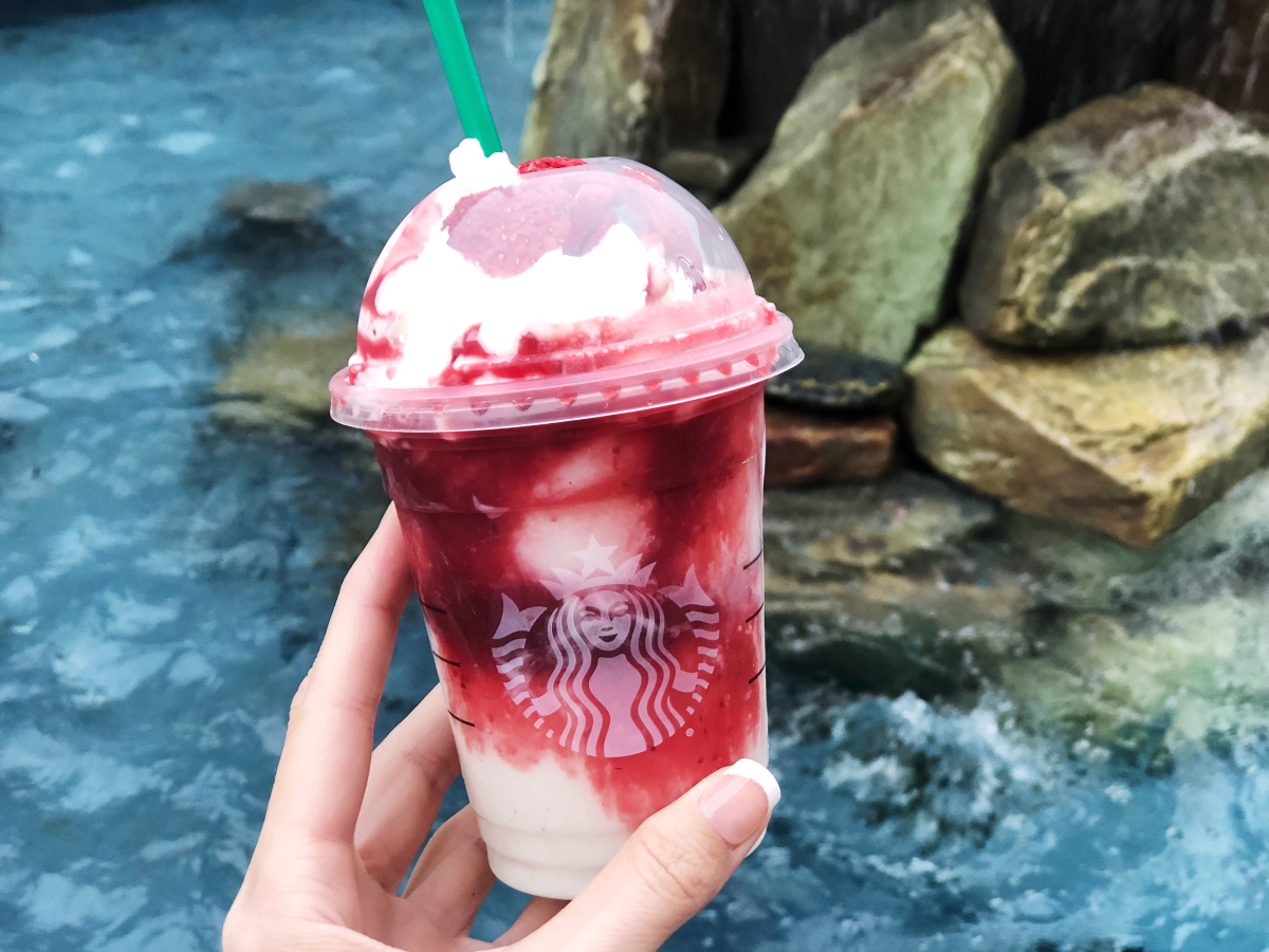 hand holding frappuccino in front of fountain