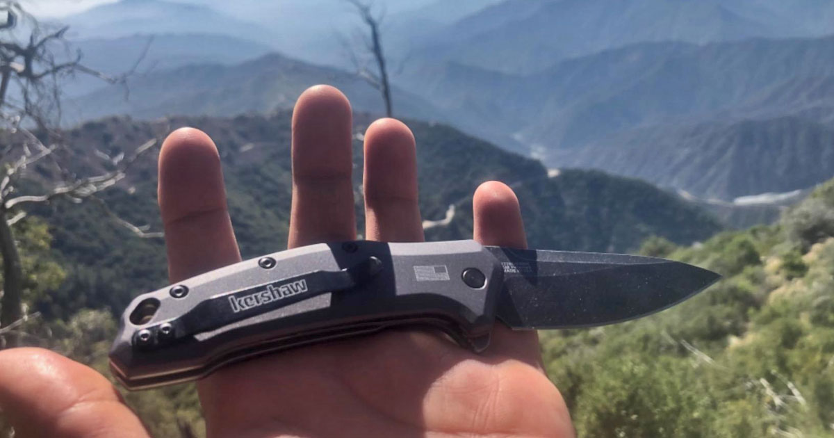 hand holding a Kershaw Link Drop Point Knife in the mountains