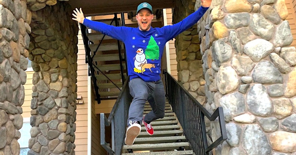 man jumping down stairs wearing ugly Christmas sweater