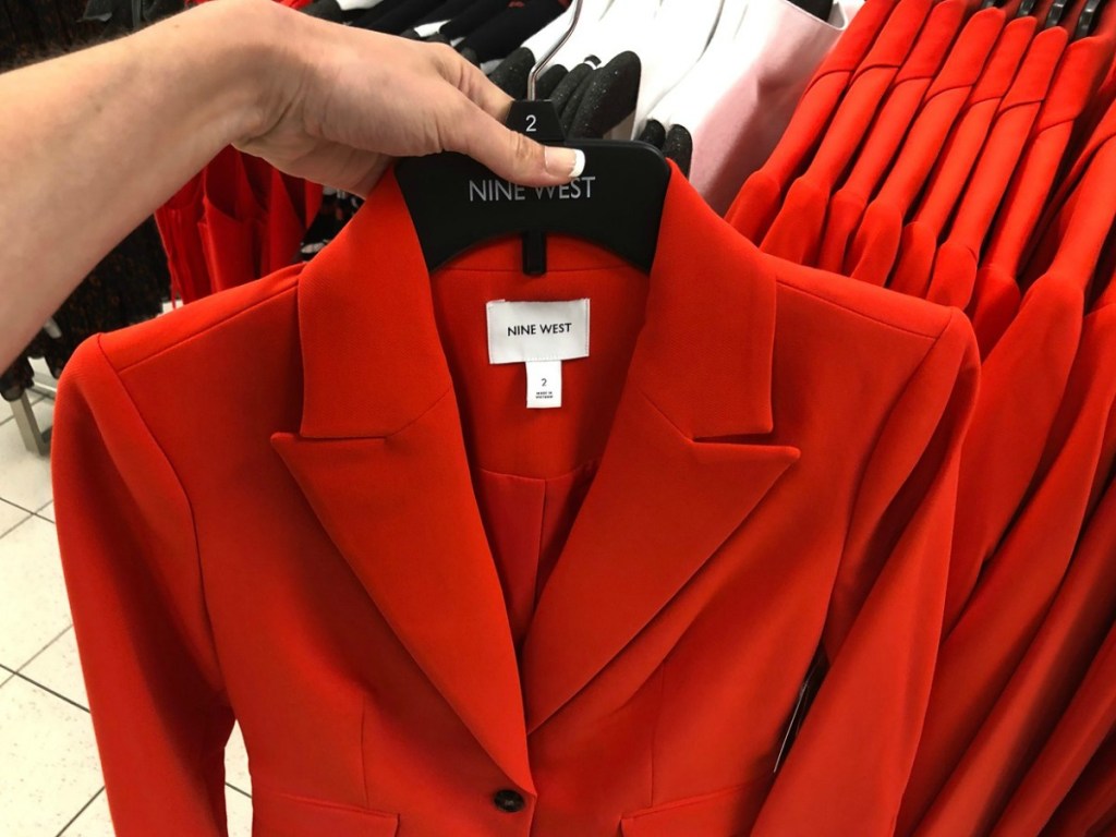 hand holding red blazer on hanger by store display