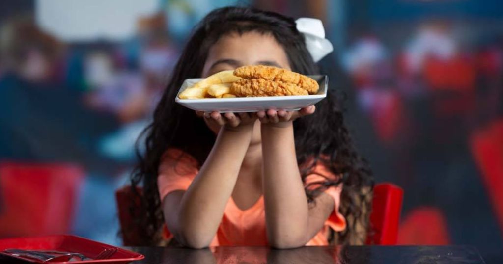 Mädchen hält Teller mit Rotkehlchen-Hühnchen, zartes Kindergericht