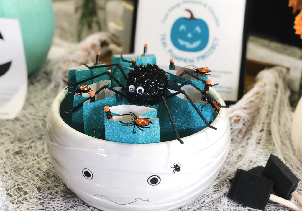 bowl of teal bags with pencils and black spider on top