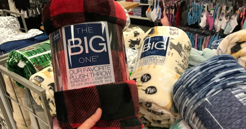 hand holding blanket by other blankets in store