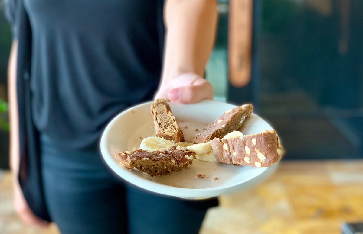 person holding toddler plate with banana and brown bread