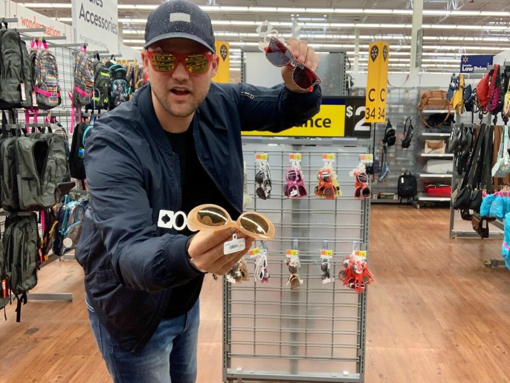 man wearing and holding glasses in store