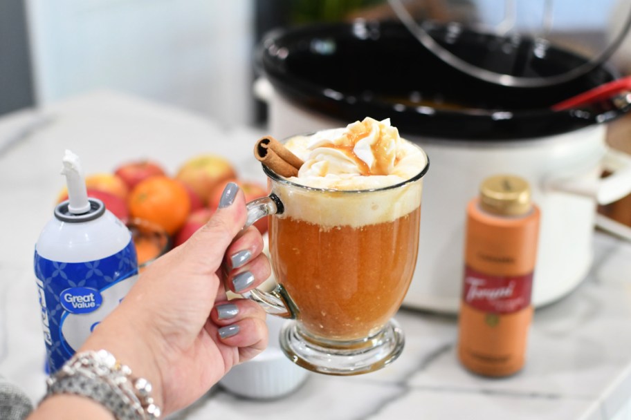 woman holding a cup of crockpot apple cider