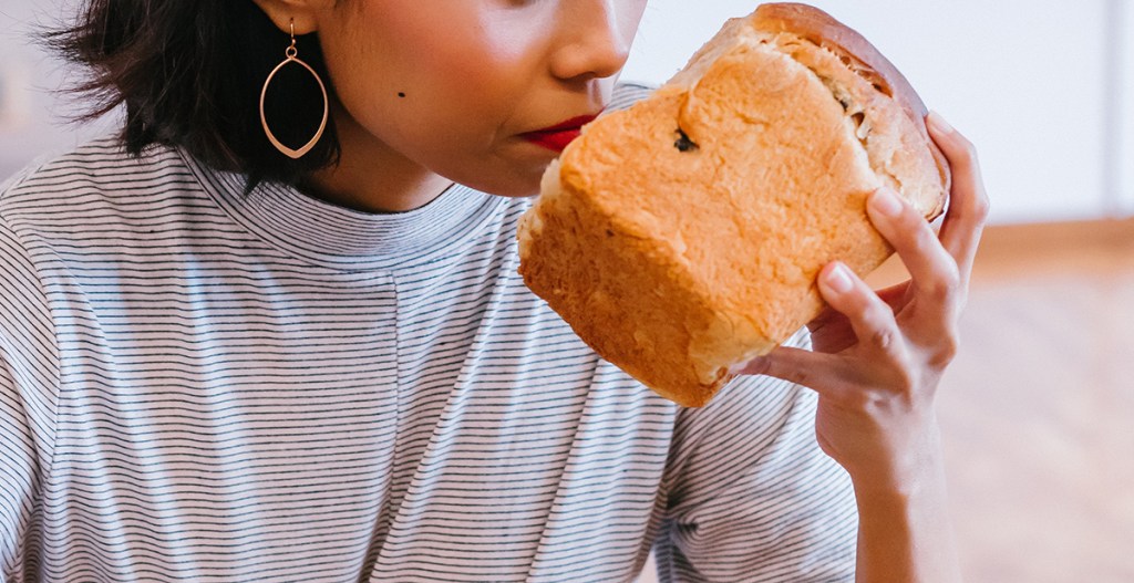 woman smelling loaf of bread