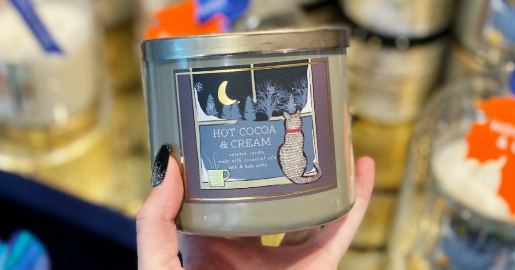 Hand holding winter hot cocoa scent 3-wick candle Bath & Body Works in-store
