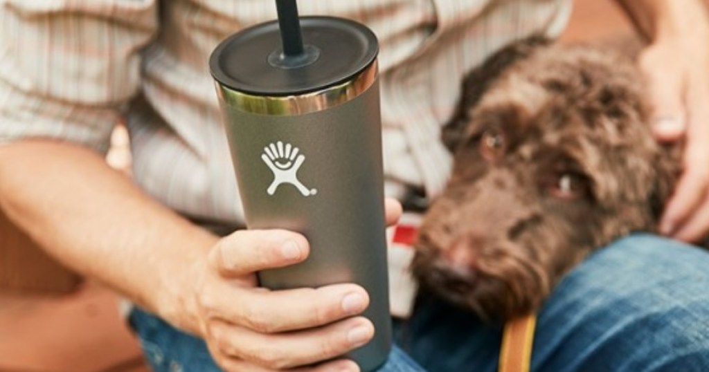 Man holding hydro flask with dog in background
