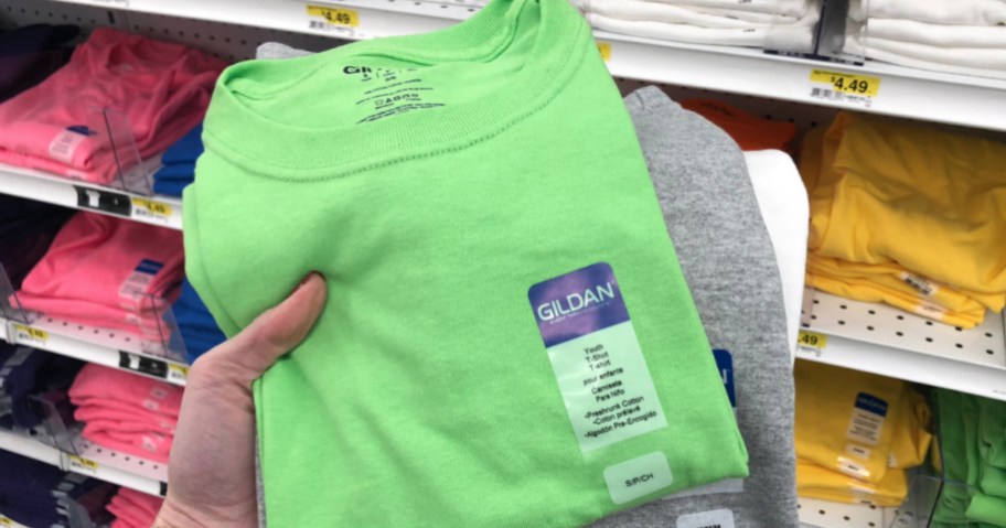 hand holding green Gildan t-shirts in store