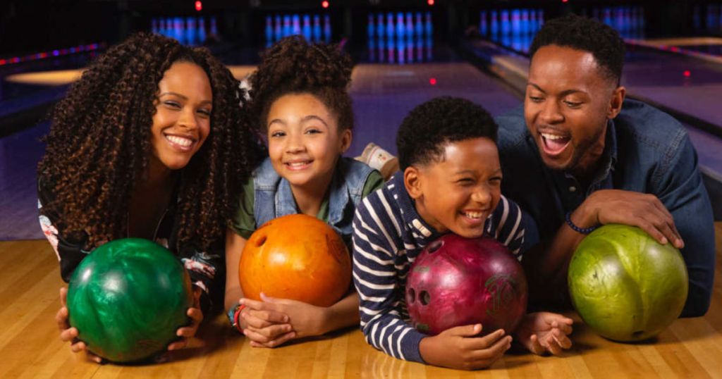 Family laughing and holding bowling balls