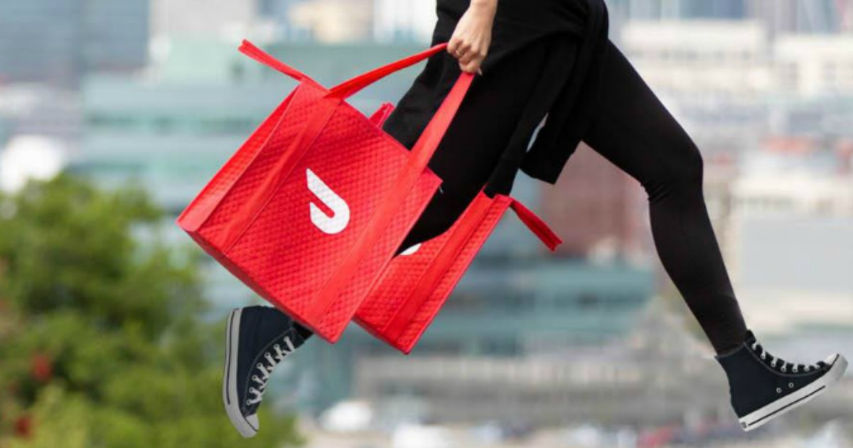 Woman carrying two DoorDash delivery bags