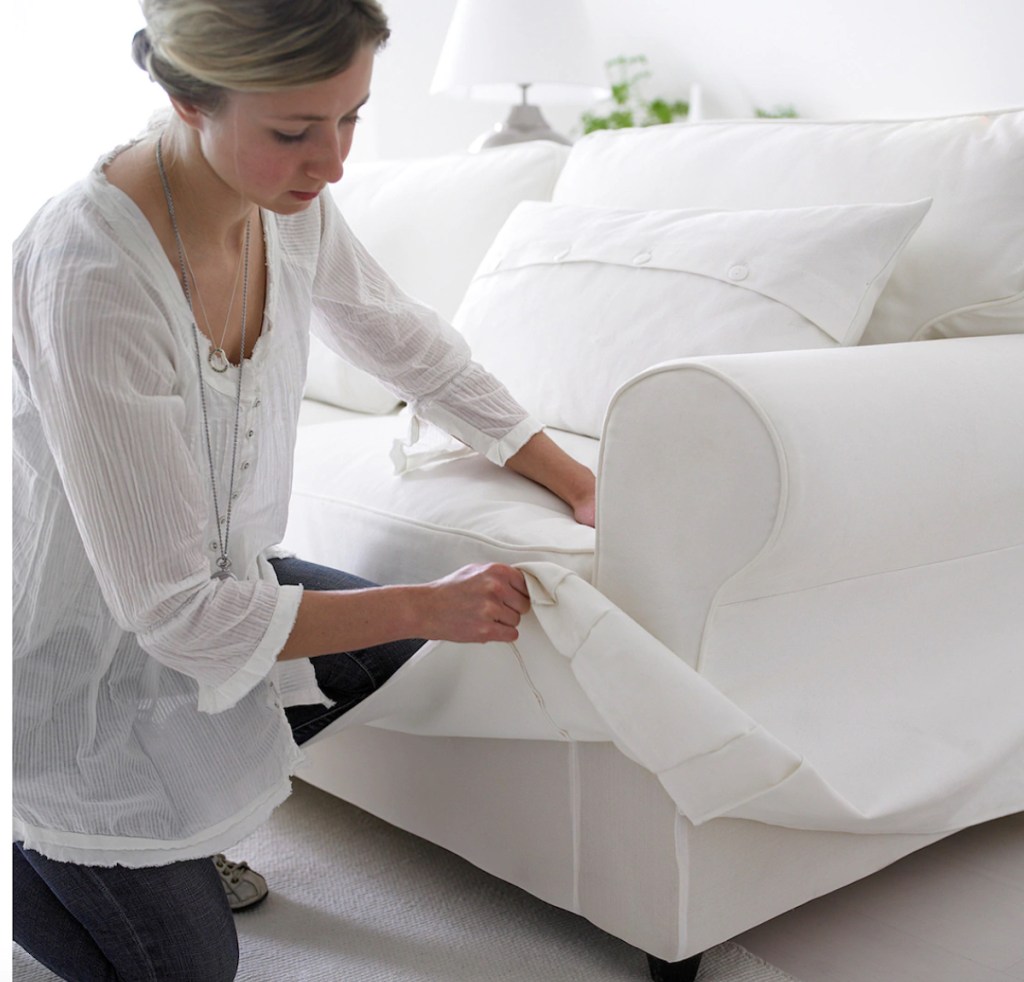 woman changing white slipcover on sofa