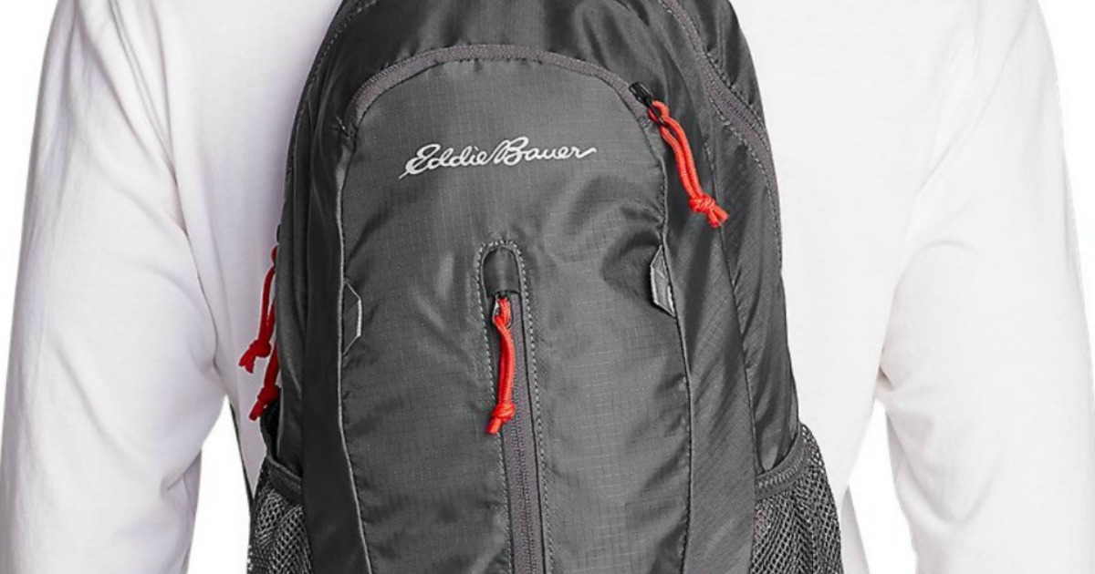 Man in a white shirt wearing an Eddie Bauer daypack backpack in gray