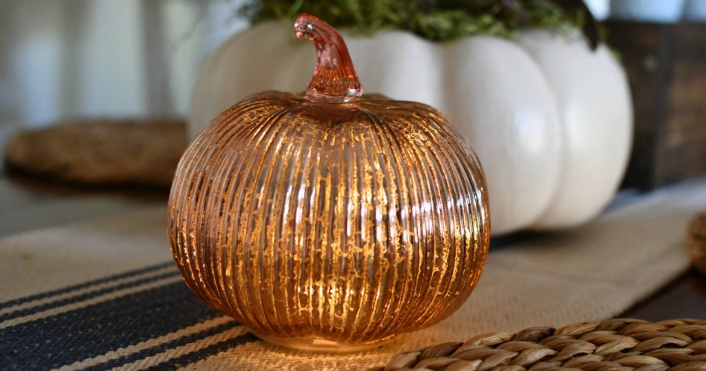 Gold Glass Light-Up Pumpkin decoration on display in front of fall decor