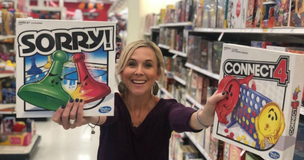 woman holding up two hasbro games