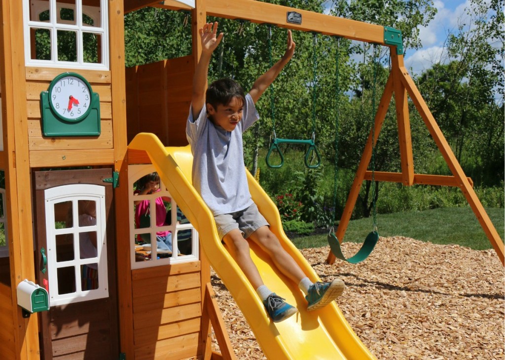 boy on slide attached to wooden playset