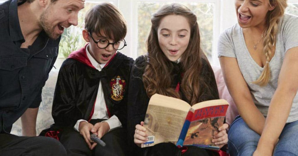 Kids wearing Harry Potter costumes and reading a Harry Potter book with their parents