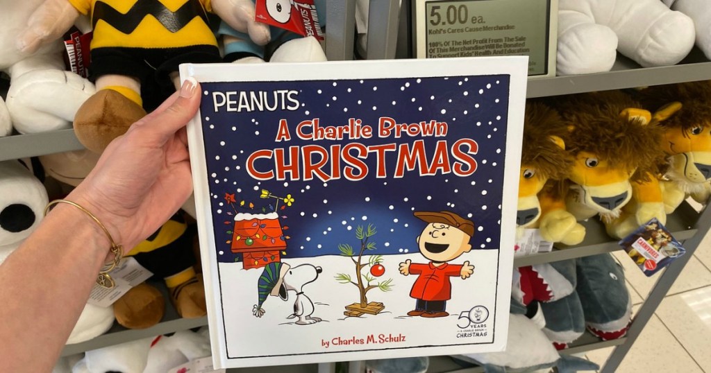 woman holding Kohl's Care's Peanuts A Charlie Brown Hardcover Christmas Book at Kohl's