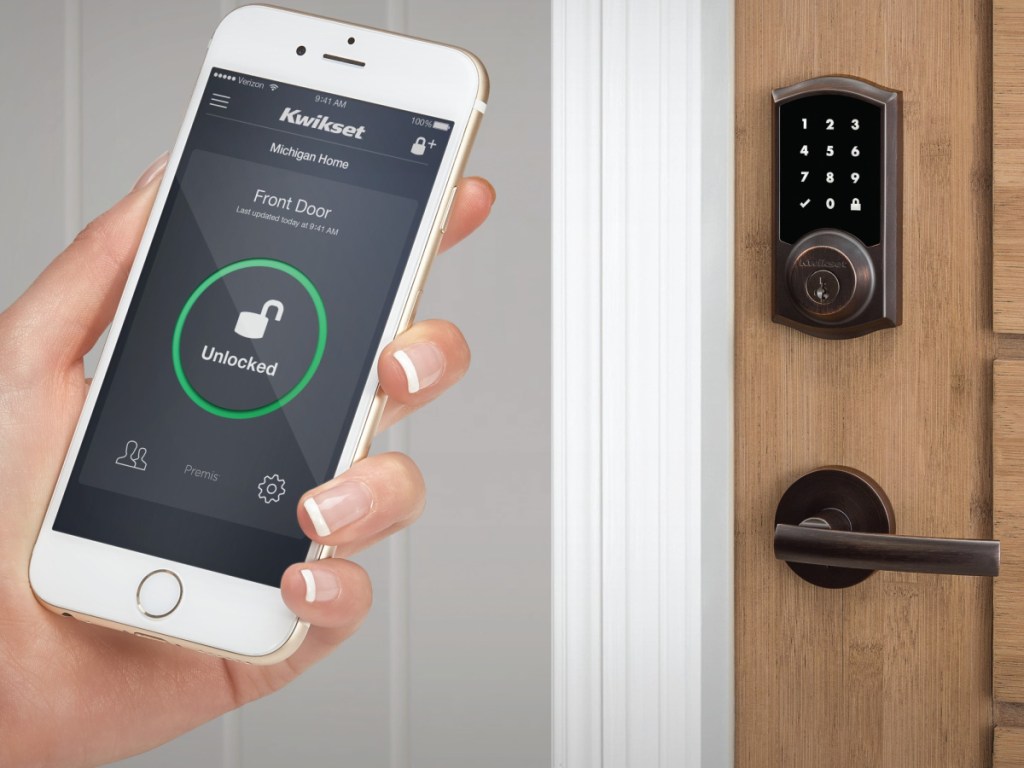 hand holding phone and door with keypad