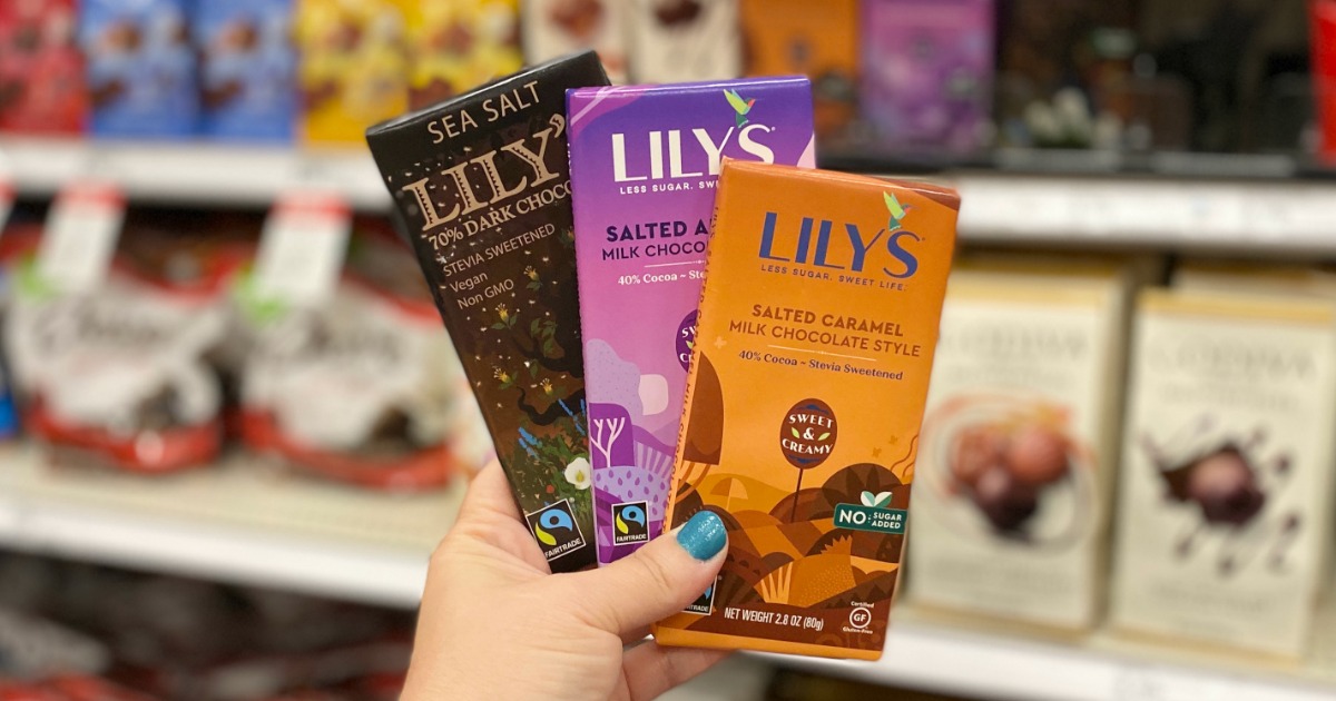 hand holding up three Lily's Chocolate Bars in front of a target candy shelf