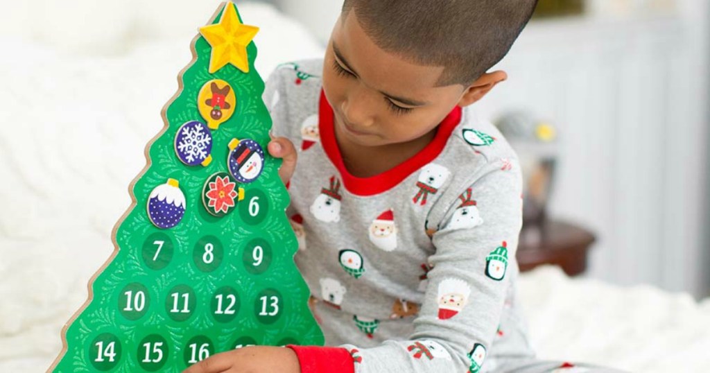 little boy in pajamas playing with a Melissa and Doug Countdown to Christmas Advent Calendar
