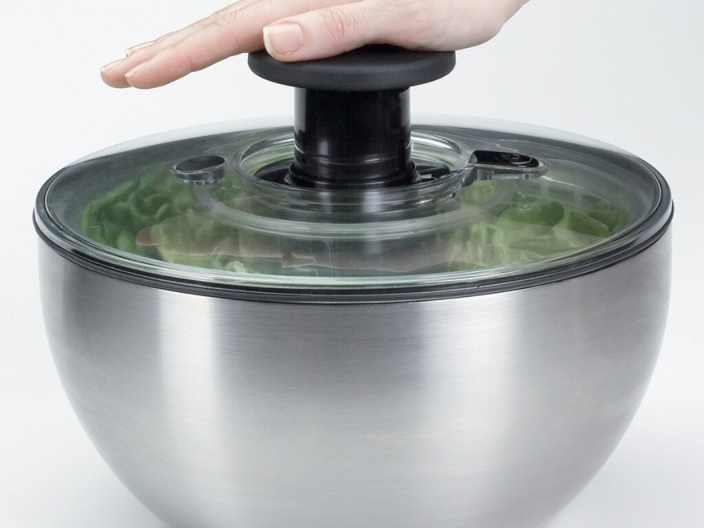 hand pushing down on salad spinner
