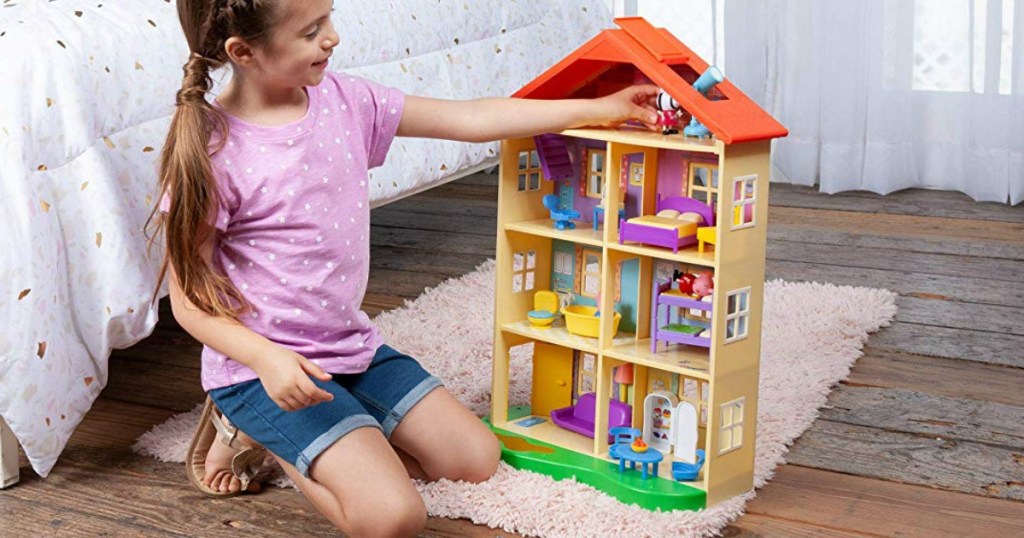 Girl playing with a Peppa Pig house playset on the floor in her bedrood
